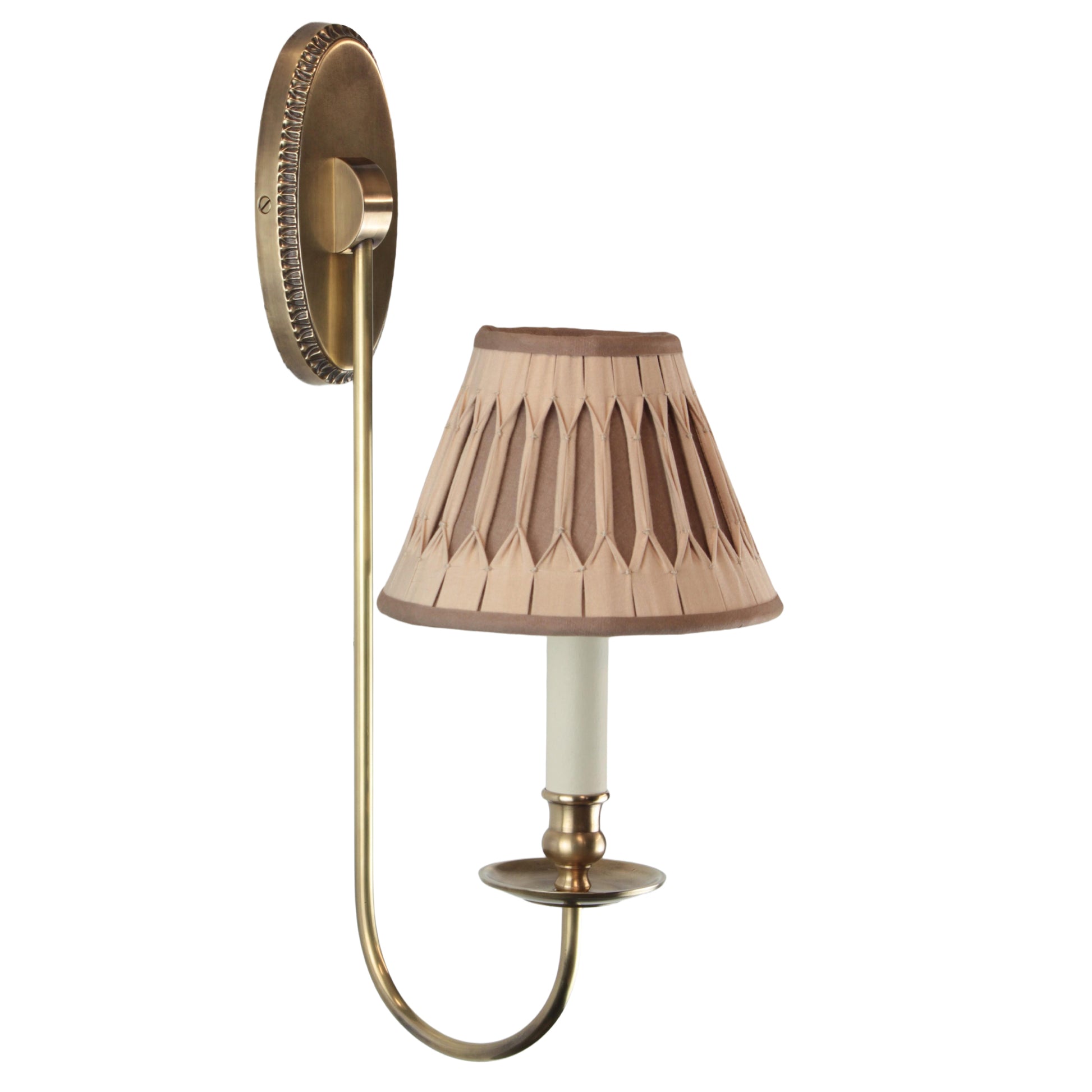 A traditional style wall lamp with a brass base and a beige lampshade featuring a geometric pattern. The lamp is turned on, showing the light and shade.